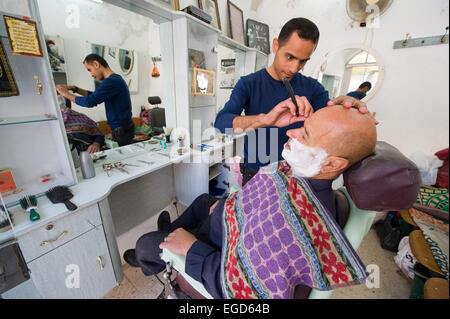 HEBRON, Israele - 10 OTT 2014: un barbiere di rasatura è un uomo nel suo piccolo barbiere nel centro della parte vecchia della città di Hebron Foto Stock