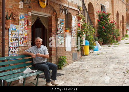 Barman locale al di fuori del suo bar nel villaggio di chiusure, val d'Orcia, Val d'Orcia, Sito Patrimonio Mondiale dell'UNESCO, provincia di Siena, Toscana, Italia, Europa Foto Stock