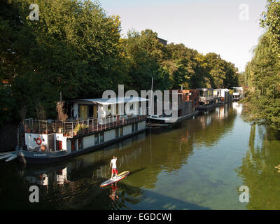 Stand up paddling su un canale nella parte anteriore della casa di barche, città anseatica di Amburgo, Germania Foto Stock