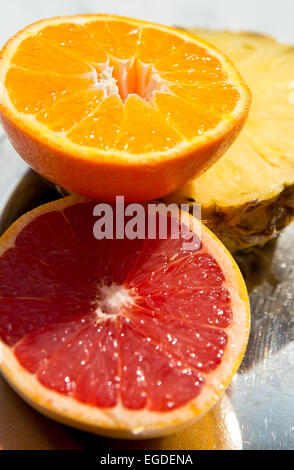 Pompelmo, arancio e ananas seduta sul display pronto a mangiare sotto la luce diretta del sole. Foto Stock