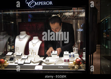 Un assistente di negozio di regolare la visualizzazione di oro e diamanti in una gioielleria finestra. Foto Stock