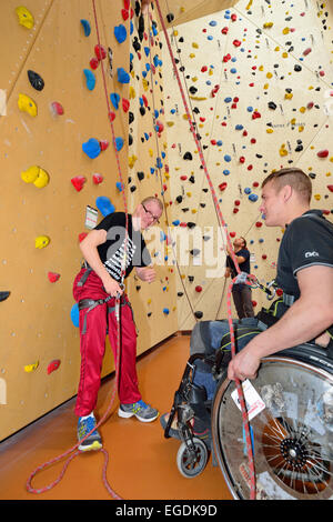 Sedia a rotelle belaying utente uomo disabile a arrampicata, arrampicata palestra Thalkirchen, Monaco di Baviera, Baviera, Baviera, Germania Foto Stock