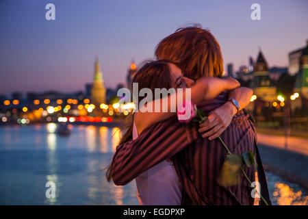 Coppia giovane abbracciando su un ponte che attraversa il fiume Moskva illuminato con il Cremlino edifici in background, Mosca, Russia, Europa Foto Stock