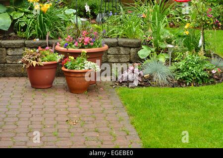 Splendidamente conservati backyard riempito con piante perenni ed annuali. Foto Stock