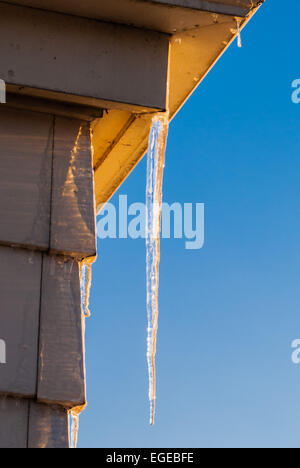 Icicle su schierata all angolo della casa sul cielo blu chiaro. Foto Stock