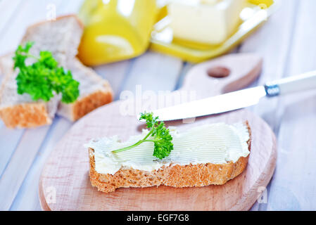 Pane con burro a bordo e su un tavolo Foto Stock