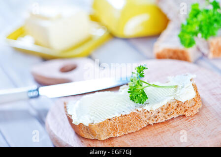 Pane con burro a bordo e su un tavolo Foto Stock