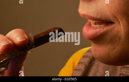 Immagine simbolica circa zucchero negli alimenti: Donna mangiare cioccolato. Foto Stock