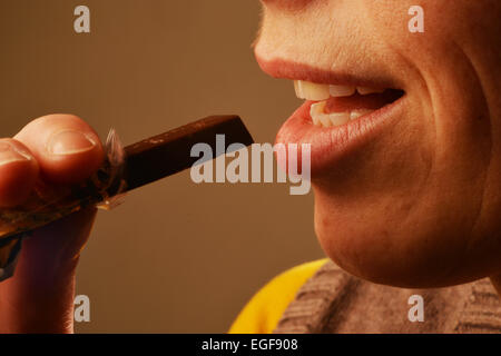 Immagine simbolica circa zucchero negli alimenti: Donna mangiare cioccolato. Foto Stock