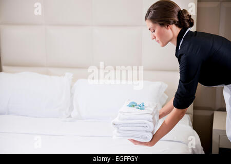 Maid rendendo letto in camera in hotel Foto Stock