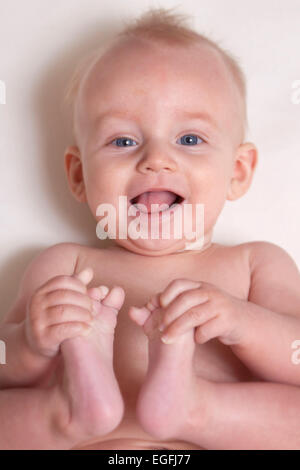 Bambino di 6 mesi tenendo le Sue dita dei piedi Foto Stock