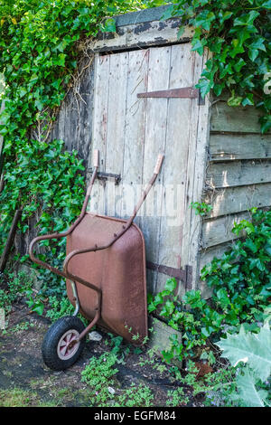 Carriola appoggiata contro la Tettoia da giardino porta Foto Stock