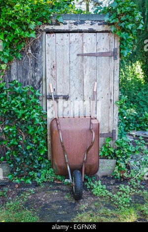 Carriola appoggiata contro la Tettoia da giardino porta Foto Stock