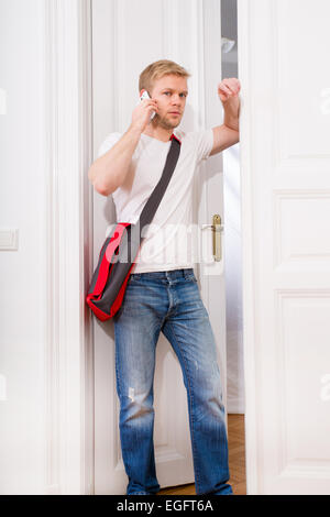 A giovani e studenti impegnati tornando a casa mentre si parla sullo smartphone. Foto Stock