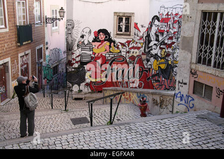 Turistica prendendo una foto di arte di strada nel quartiere di Alfama di Lisbona Foto Stock