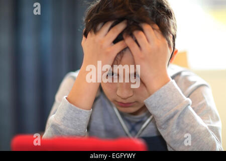 Confuso o stanco ragazzo giocando con il computer tablet Foto Stock