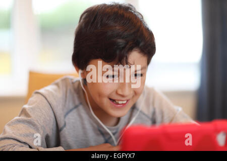 Giovane ragazzo sorridente giocando con il computer tablet Foto Stock