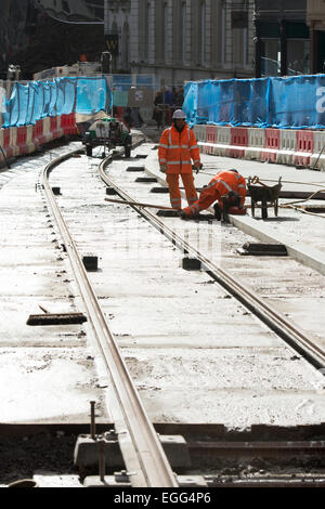 Birmingham, West Midlands, Regno Unito. Il 24 febbraio, 2015. Operai laici tracce in Corporation Street come parte del centro città estensione del Midland Metro Tram. Questa fase di estensione, tra Snow Hill e la nuova strada stazioni ferroviarie, è dovuto per essere poi completato nel 2015. Ulteriori estensioni a Birmingham Town Hall e Centenary Square sono previste per il completamento nel 2017. Credito: Colin Underhill/Alamy Live News Foto Stock