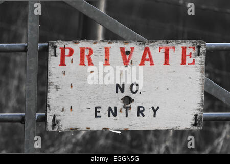 Non privato entrata segno sulla porta di metallo con prominenti rosso e lettere in nero su bianco spicca contro sfondo monocromo Foto Stock