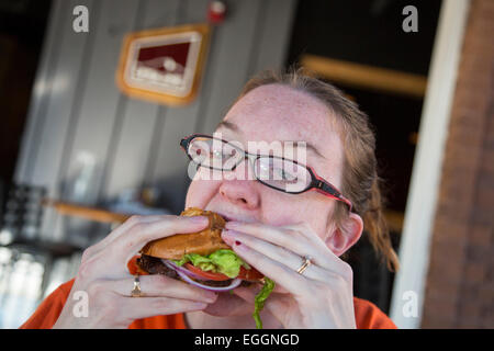 Wheat Ridge in Colorado - una giovane donna cerca di ottenere la sua bocca attorno un cheeseburger presso la Colorado Plus Brew Pub. Foto Stock