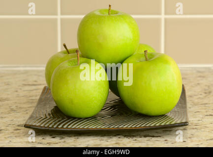 Fresche e mature mele verdi nella piana della piastra quadrata sul bancone Foto Stock
