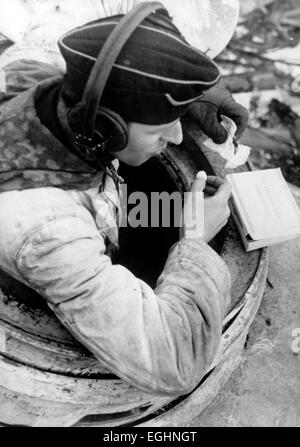 Un'immagine di propaganda nazista mostra un soldato carro armato della Wehrmacht tedesca che scartava la sua fornitura di cibo "per i combattenti in combattimento" durante un periodo di noia nei combattimenti sul fronte Narva durante la seconda guerra mondiale nell'aprile 1944. Fotoarchiv für Zeitgeschichtee - SENZA FILI - Foto Stock