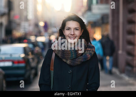 Ritratto di un elegante piuttosto giovane donna in autunno la moda a piedi la città guardando la telecamera. Foto Stock