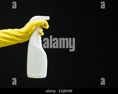 Mano umana con guanto di gomma holding spray di pulizia bottiglia, su sfondo nero Foto Stock