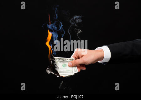 Stretta di mano maschio holding bruciando denaro dollaro Foto Stock