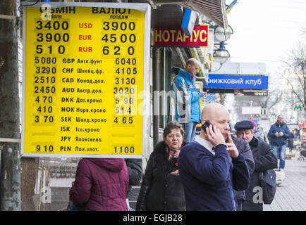 La gente passa le valute tasso di cambio piastra centro di Kiev. Il 25 febbraio, 2015. Per l'Ucraina grivna sono crollati più di cento per cento contro il dollaro a un nuovo record basso su Gennaio 6, 2015 dopo la banca centrale ha abbandonato i suoi sforzi per sostenere la valuta. © Igor Golovniov/ZUMA filo/Alamy Live News Foto Stock