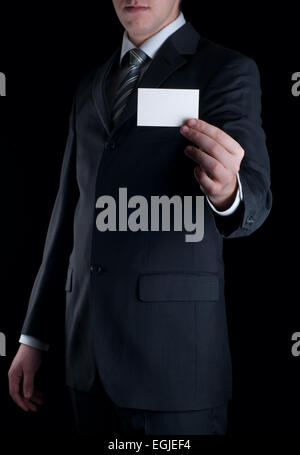 Uomo d'affari di consegnare un fustellato business card su sfondo nero Foto Stock