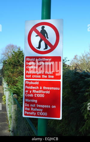 Segno di Cardiff in inglese e gallese avviso di persone a non attraversare la linea ferroviaria o infedeltà sulla ferrovia Foto Stock