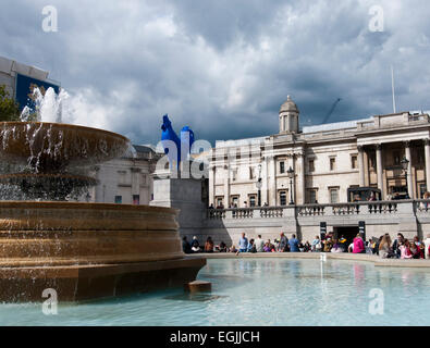 Fontana con Blue galletto scultura al quarto zoccolo in background a Trafalgar Square, Londra Foto Stock