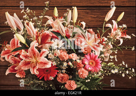 Fiore coloratissimo bouquet di rose, gigli e garofani nella parte anteriore della parete in legno Foto Stock