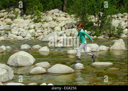 Ragazza saltando su rocce nel fiume Solenzara, Corse-du-Sud, Corsica, Francia Foto Stock