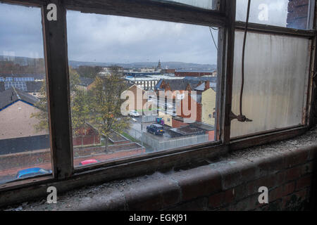 Guardando fuori attraverso una sporca finestra di fabbrica con gocce di pioggia sul vetro Foto Stock