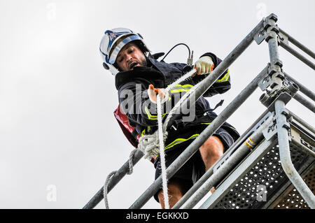 Belfast, Irlanda del Nord. 8 agosto 2013 - un vigile del fuoco tira un tubo flessibile oltre 100ft su un gantry all'ultimo evento vigile del fuoco, mondo di polizia e dei vigili del fuoco di giochi (WPFG) Foto Stock