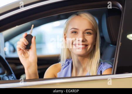 Donna felice getting chiave auto in auto show o salon Foto Stock