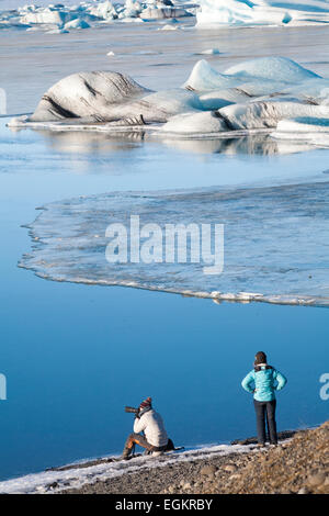 Fotografo che fotografa lo splendido paesaggio della laguna Glaciale di Jokulsarlon, ai margini del Parco Nazionale di Vatnajokull, in Islanda, nel mese di febbraio Foto Stock