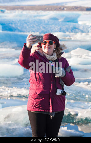 Donne turistiche prendere un selfie alla Laguna Glaciale di Jokulsarlon, sul bordo del Parco Nazionale di Vatnajokull, Islanda nel mese di febbraio Foto Stock