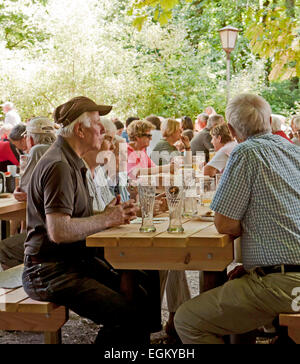 La gente seduta e rilassante drink all'aperto presso uno dei tanti stagione giardini della birra di Monaco di Baviera Germania Foto Stock