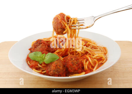 Spaghetti con polpettine di carne in una ciotola con una forchetta su una tavola di legno Foto Stock