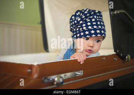 Bellissimo bambino guardando sopra la spalla seduta in un passeggino rétro Foto Stock