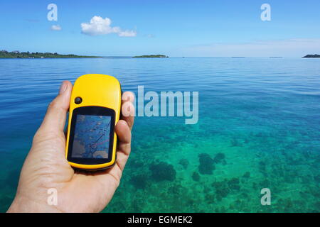 Navigatore satellitare GPS in mano al di sopra di calma e chiara acqua con isola tropicale all'orizzonte, il mare dei Caraibi, Panama Foto Stock