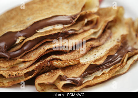 Crespelle sottili o blinis con crema di cioccolato sulla piastra Foto Stock