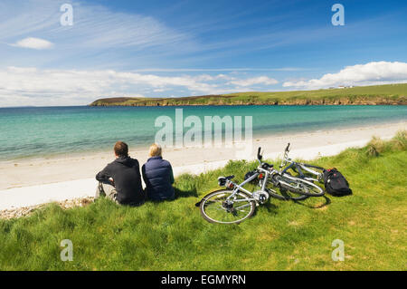 Giovane uomo e donna appoggiato accanto a loro bicicletta pedalando su South Ronaldsay, Orkney Islands, Scozia. Foto Stock