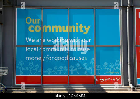 Slogan al di fuori del negozio Tesco in Ellesmere, Shropshire circa il lavoro con le comunità locali per raccogliere fondi Foto Stock