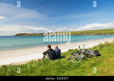 Giovane uomo e donna appoggiato accanto a loro bicicletta pedalando su South Ronaldsay, Orkney Islands, Scozia. Foto Stock