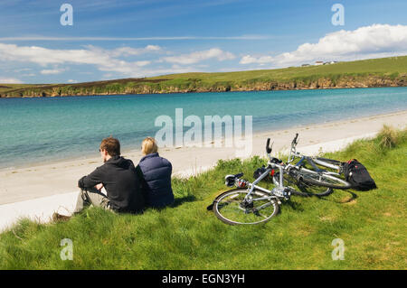 Giovane uomo e donna appoggiato accanto a loro bicicletta pedalando su South Ronaldsay, Orkney Islands, Scozia. Foto Stock