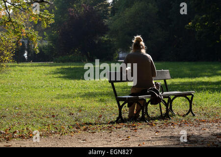 Attraente ragazza leggendo un libro in un caldo pomeriggio di sole nel parco Lazienkowski, Varsavia Foto Stock